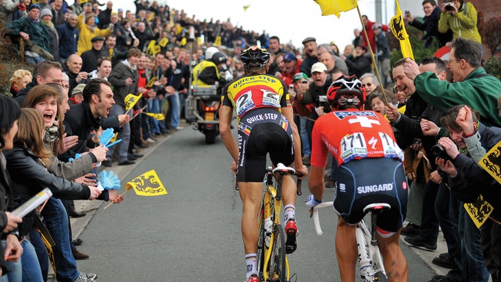 Boonen and Cancellara ride up a narrow road with fans cheering on either side