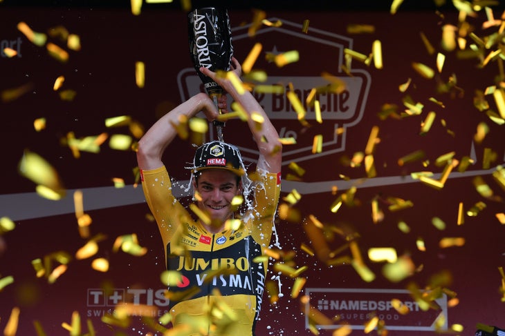 Van Aert tries a new way of washing off the dust as he celebrates on the podium.