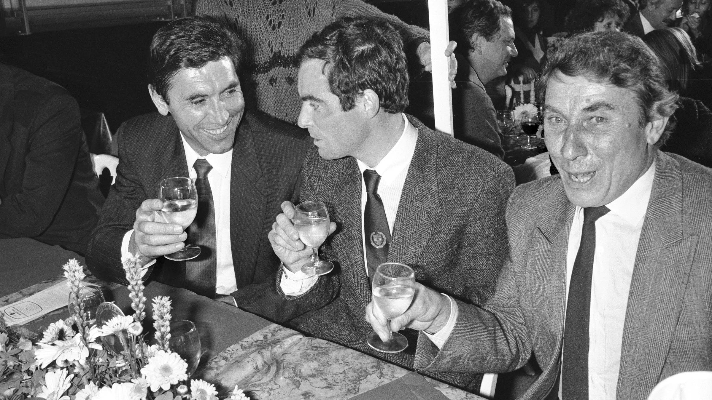 Eddy Merckx, Bernard Hinault and Jacques Anquetil, enjoy a glass of wine, France, circa 1975.