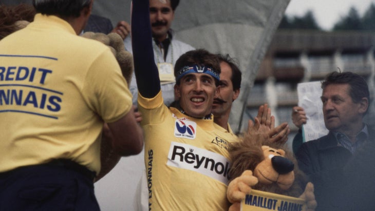 Delgado, wearing yellow, holds up his flowers for winning