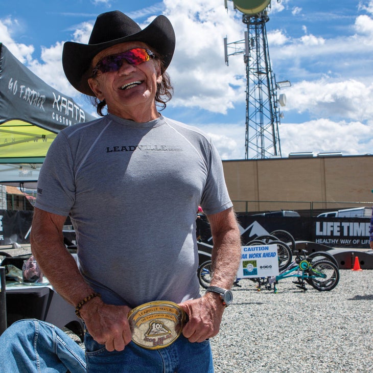Chlouber smiling in a t-shirt, cowboy hat, and massive gold belt buckle
