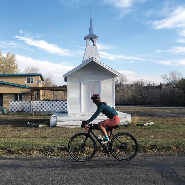 Woman on her bike, looking at a small white church