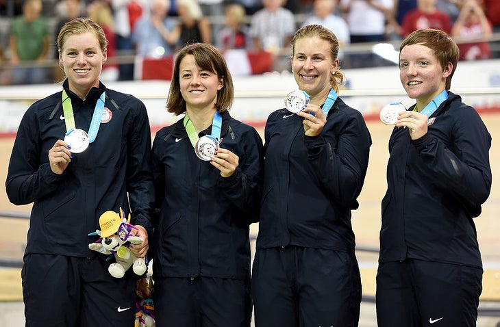 Four women holding up silver medals