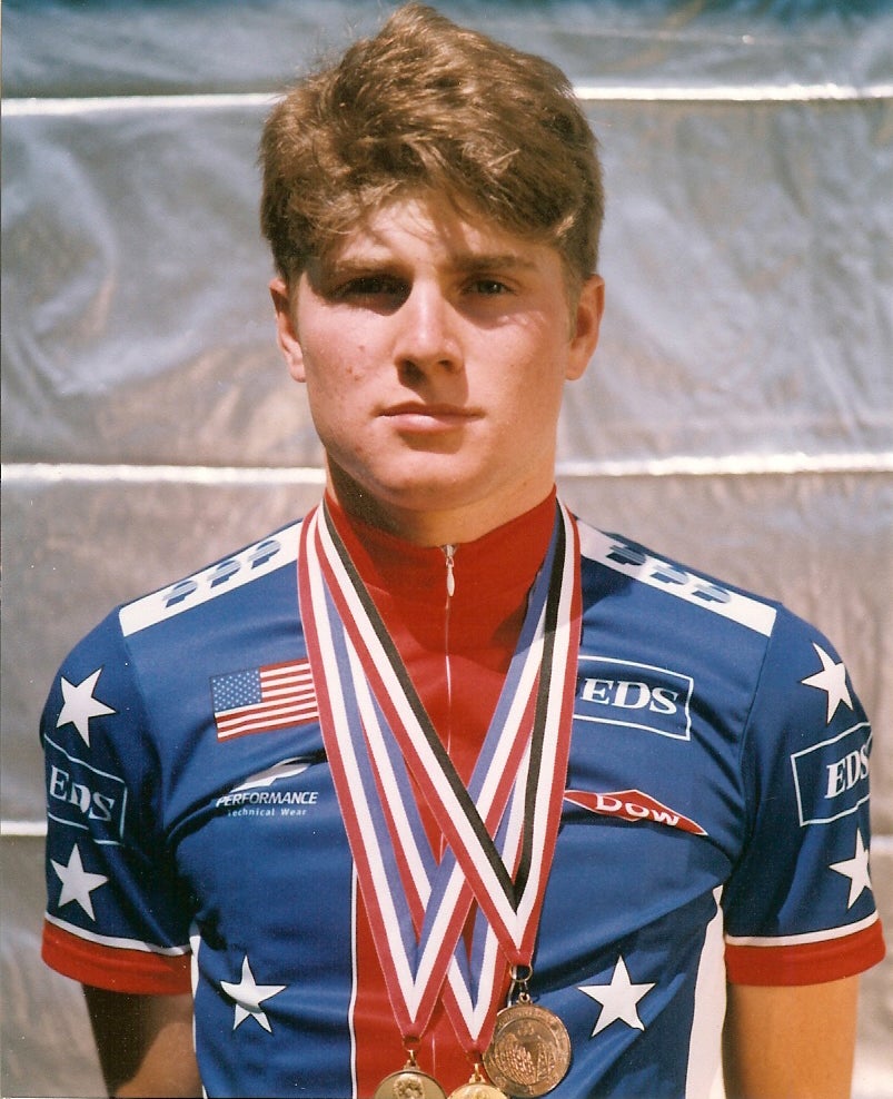 James Hibbard in a Team USA cycling kit, wearing multiple medals