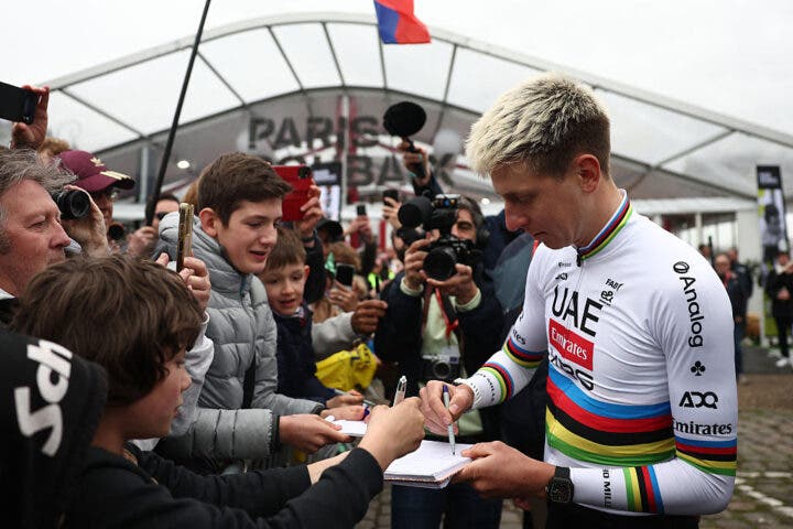 UAE Team Emirates XRG's Slovenian rider Tadej Pogacar (R) signs autographs during the teams' presentations event on the eve of the 123rd edition of the Paris-Roubaix one-day classic cycling race, 258.3 km between Compiegne and Roubaix, in Compiegne, northern France, on April 11, 2026. (Photo by Anne-Christine POUJOULAT / AFP via Getty Images)